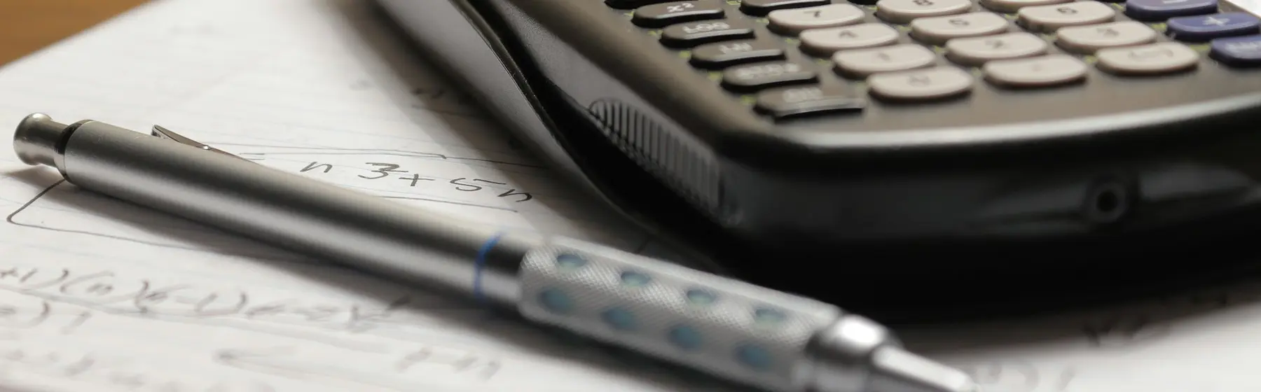 Une calculatrice et un stylo posés sur des documents financiers