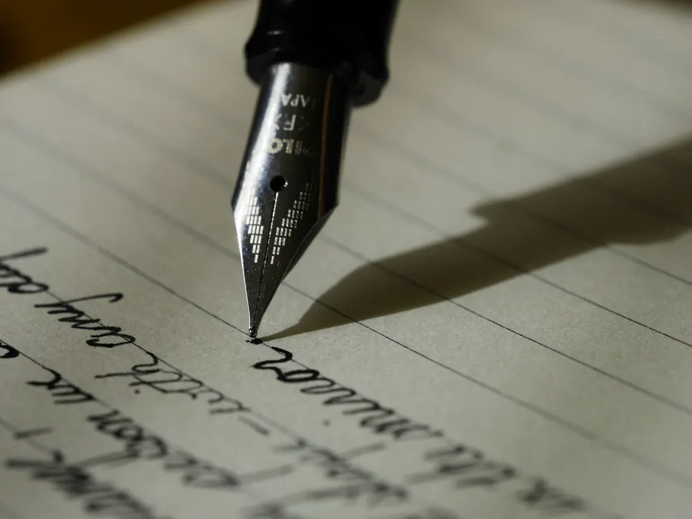 Une main rédige un testament olographe à la plume